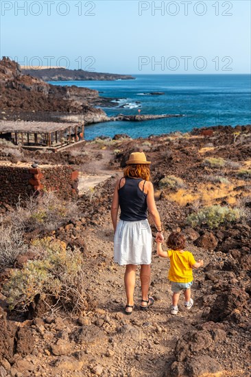 Mother and son on vacation walking on a path along the beach of Tacoron on El Hierro