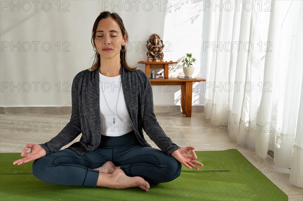 Woman meditating on her yoga mat in a peaceful setting with a Buddha statuette