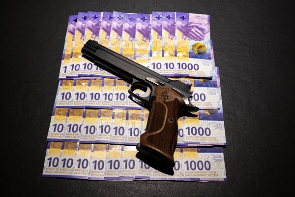 Elegant Semiautomatic 9mm Handgun with Swiss Helvetia Symbol Leaning on Swiss Franc 1000 Banknote in Switzerland