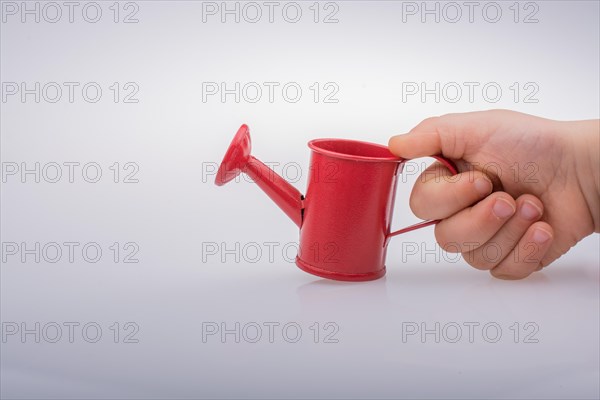 Hand holding a watering can on a white background