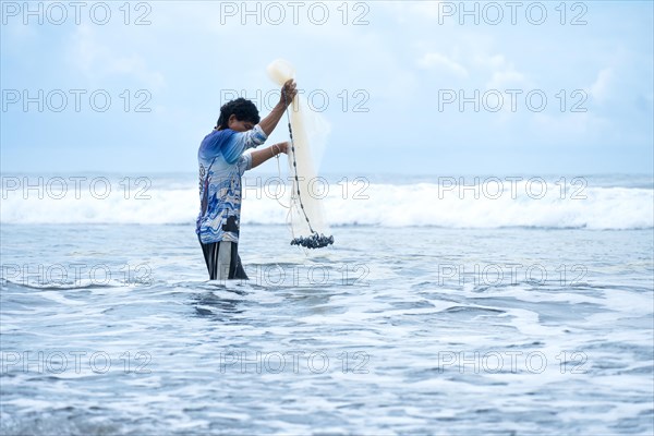 Side view of a fisherman in the sea preparing his net. Concept of sufficiency economy