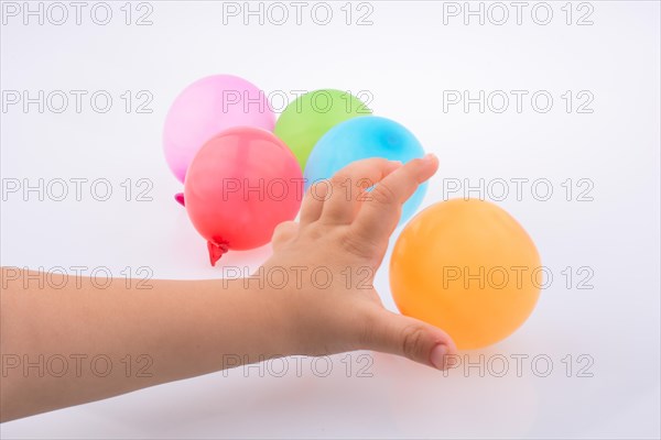 Hand holding a Colorful small balloon with colorful balloons on the white background
