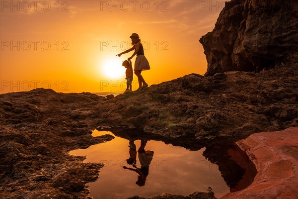 Silhouette of mother and son walking in the sunset on the beach of Tacoron in El Hierro