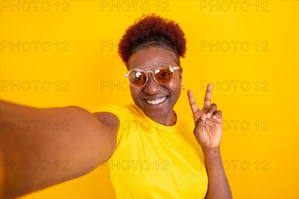 Young african american woman isolated on a yellow background smiling and making a selfie