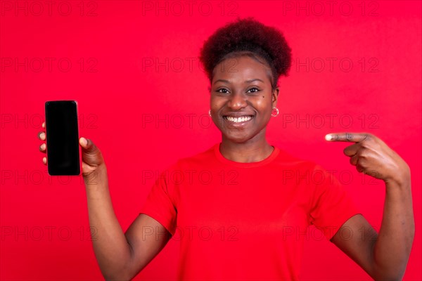 Young african american woman isolated on a red background with mobile pointing gesture