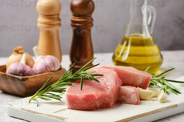 Closeup view of raw fresh pork fillet cut on slices on kitchen table with spice