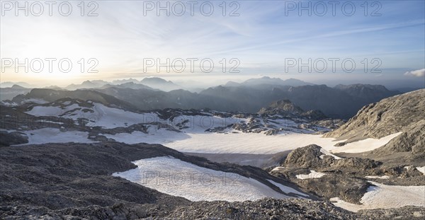 View of rocky plateau with glacier and remnants of snow in the evening light