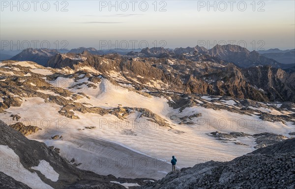 View of rocky plateau with snow and glacier at sunrise