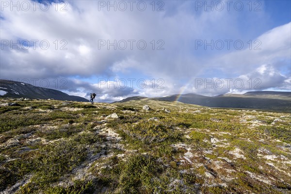 Mountaineer in the mountains with rainbow