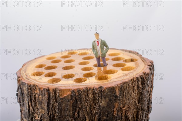 Little man figurine places on a wooden log