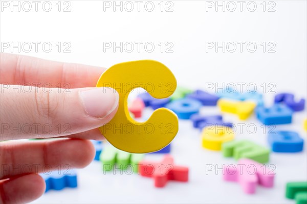Letter C in hand beside colorful alphabet letter blocks scattered randomly