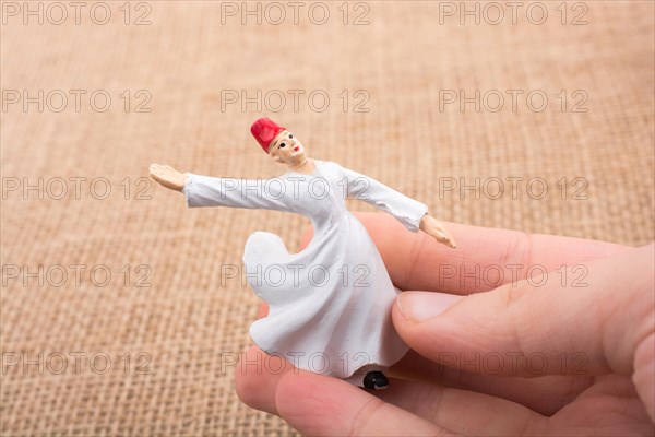 Hand holding a white color Sufi Dervish figurine in hand