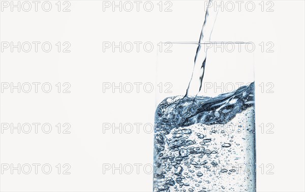 Water is poured bubbling into a clear glass