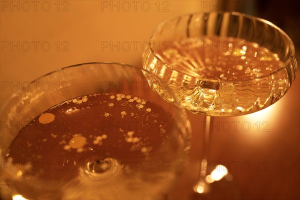 Two glasses with champagne on a wooden table surface. They are reflecting soft sunshine rayson. Sparkling wine with beautiful boke spots. Copy space. Close up