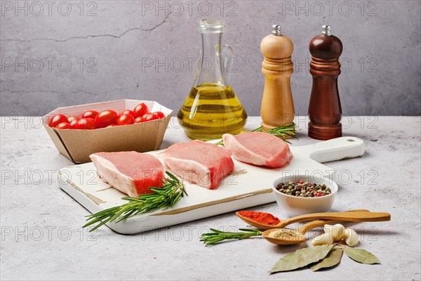 Three raw pork escalopes on cutting board surrounded with spice