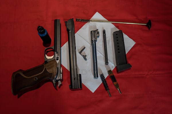 Cleaning a Dirty Disassembled Handgun on Red Towel in Switzerland