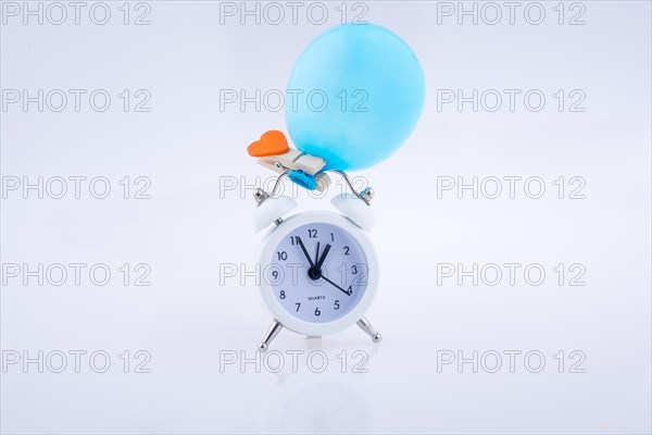 Alarm clock and a balloon with a heart on white background