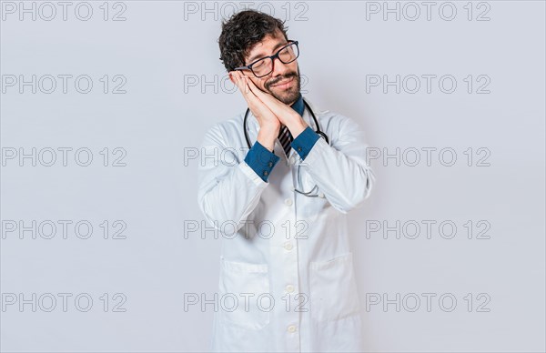 Doctor making sleep gesture isolated. Handsome doctor making sleep gesture with palms on his cheeks