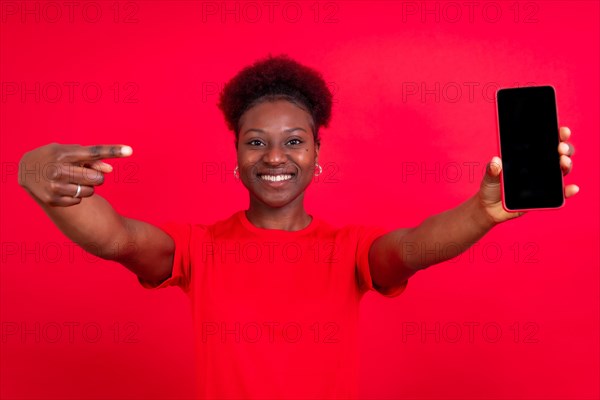 Young african american woman isolated on a red background with mobile pointing gesture