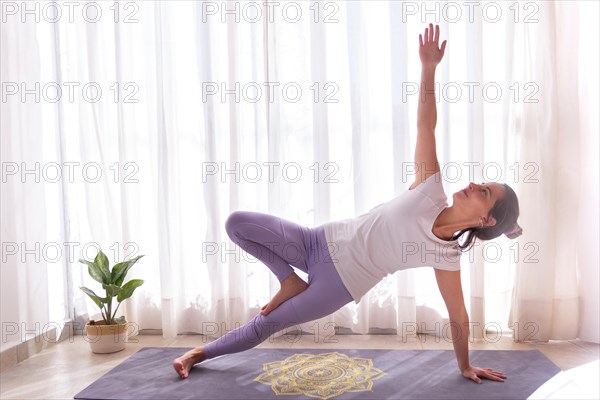 Woman practicing yoga in a bright room on mandala yoga mat