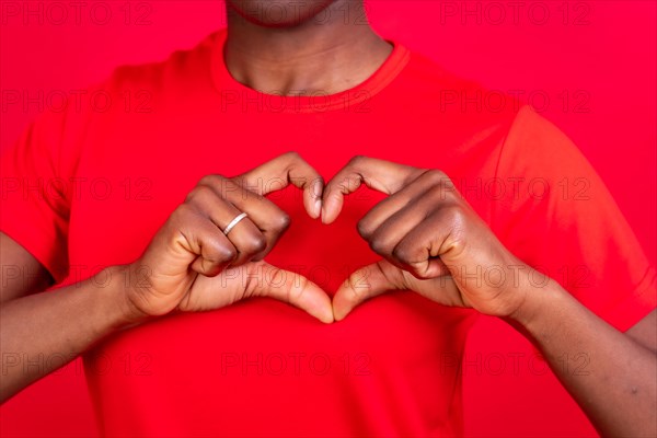Young african american woman isolated on a red background smiling and heart gesture
