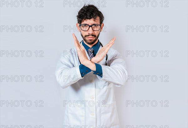 Young doctor making stop sign with hands isolated. Doctor making a stop gesture with palms on isolated background