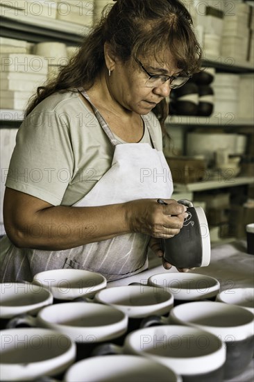 Craftswoman making the sgraffito on a piece of pottery