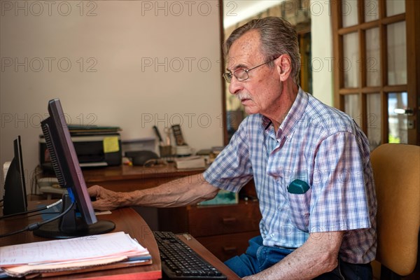 Older man sitting in front of his computer at home