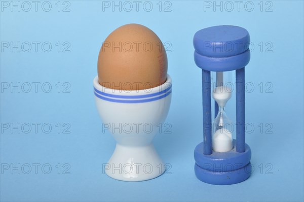 Boiled egg and hourglass on a blue background