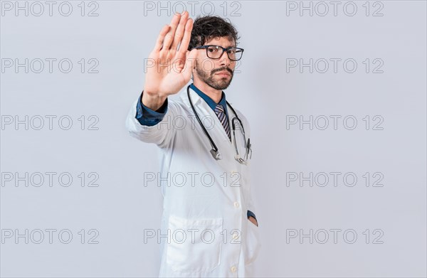 Serious doctor making stop gesture on isolated background