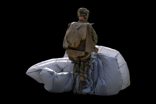 Military Parachuter Standing with His Parachute on Black Background in Switzerland