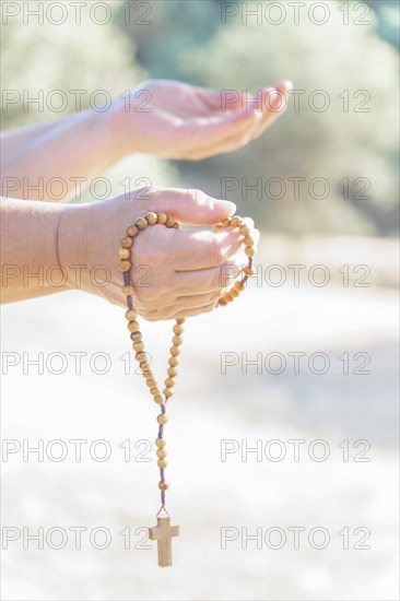 Woman's hands holding a Christian rosary with a cross