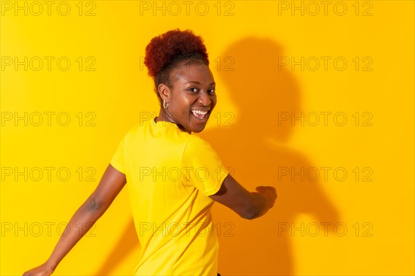 Young african american woman isolated on a yellow background smiling and dancing