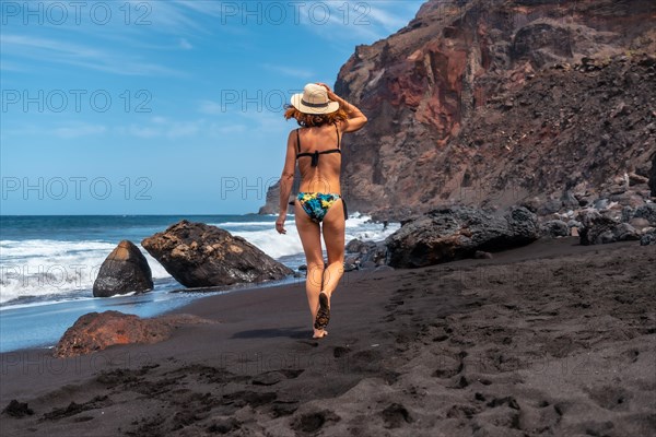 A woman tourist on the black volcanic sand beach of El Ingles in Valle Gran Rey on La Gomera