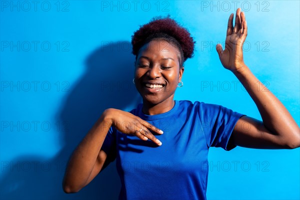 Young african american woman isolated on a blue background smiling and dancing