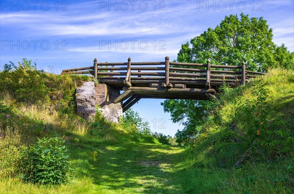 Small wooden bridge over a field and hiking path in front of Laeckoe Castle at Lake Vaenern