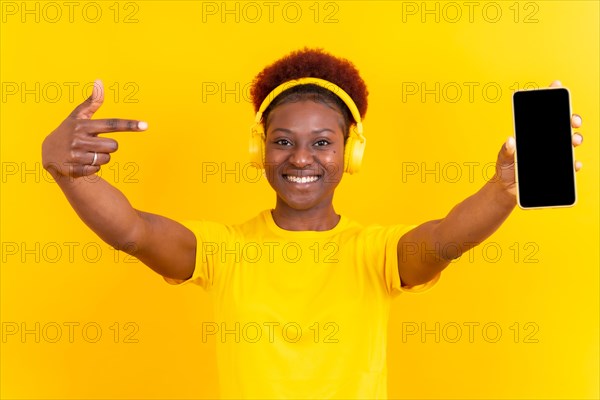 Young african american woman isolated on a yellow background with mobile pointing gesture