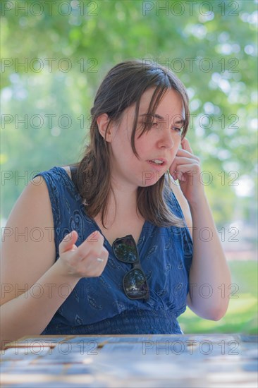 Close-up of a young woman dressed in blue with sunglasses seated at a park table playing card games