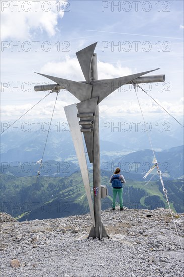 Mountaineer at the summit cross on the Hochkoenig