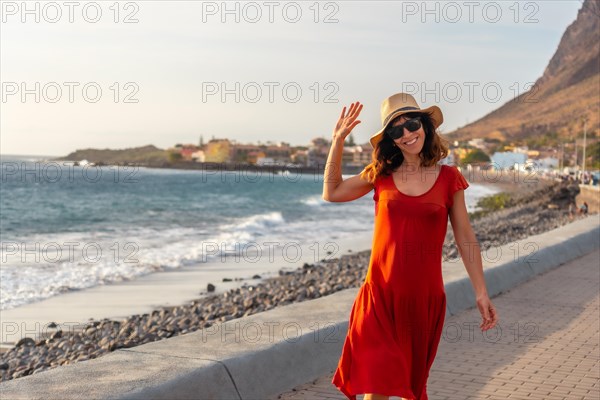 Woman tourist smiling at sunset walking on the beach of the town of Valle Gran Rey in La Gomera