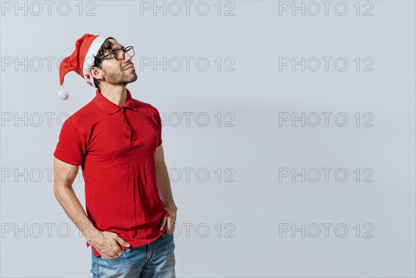 Christmas man with hand in pocket looking at copy space. Guy in Christmas hat with hands in his pocket looking at a promo