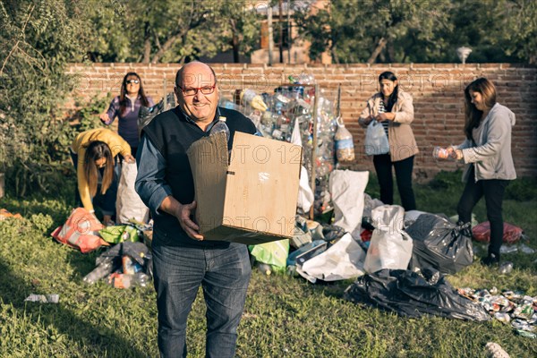 Group of happy volunteers separating recycling material. A man and group of women organizing material for recycling. Environmentalism