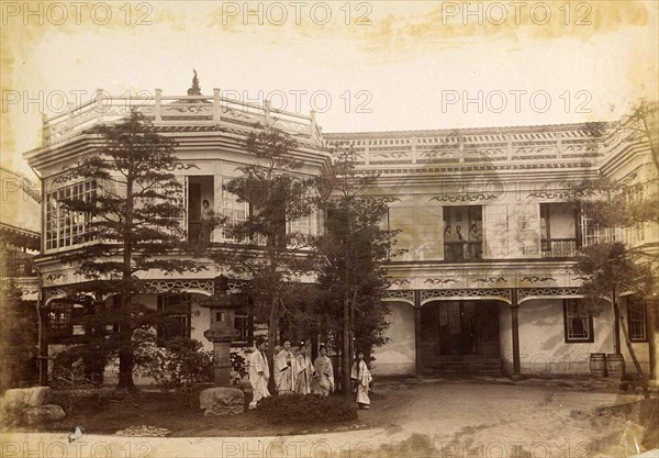 Geishas posing in front of and on the gallery of a house in Japan