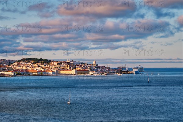 View of Lisbon over Tagus river from Almada with yachts tourist boats and moored cruise liner on sunset with dramatic sky. Lisbon