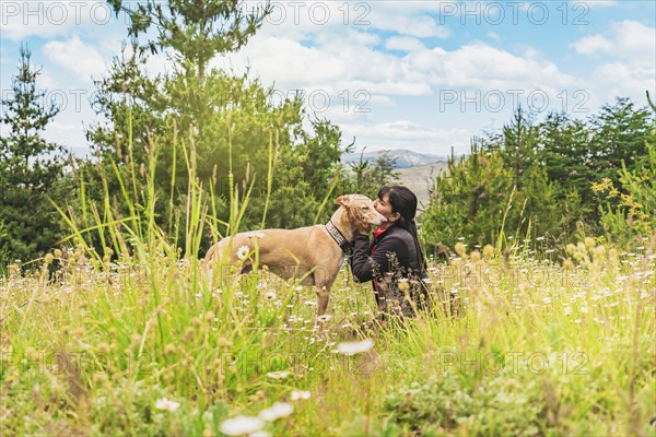 Beautiful woman kissing her greyhound dog outdoors. Concept of companion animal. October 4th World Pet Day