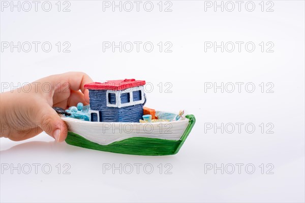 Little colorful model boat in hand on white background