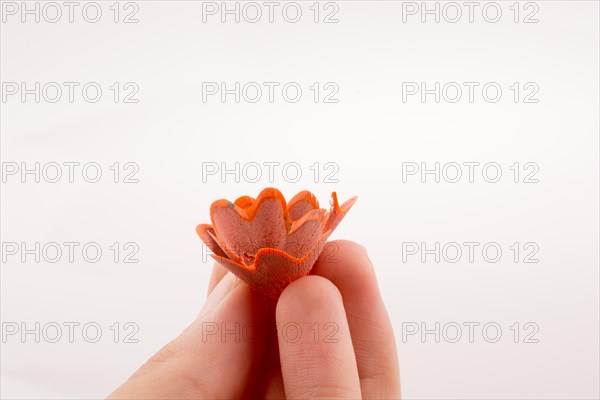 Color pencils shavings at the top of fingers on white background