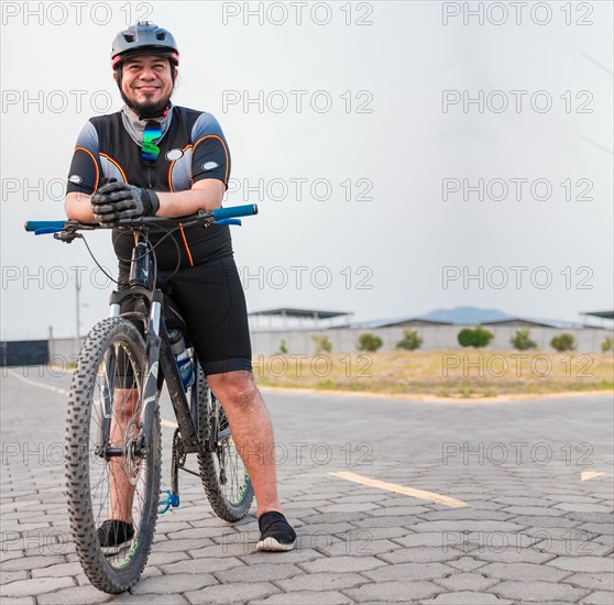 Portrait of cyclist on his bike looking at the camera with copy space. Chubby male cyclist in sportswear riding a bicycle outdoors