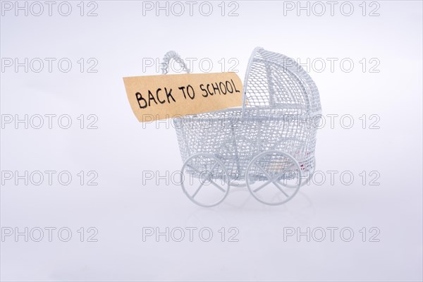 Toy baby carriage made of metal on white background has a sign