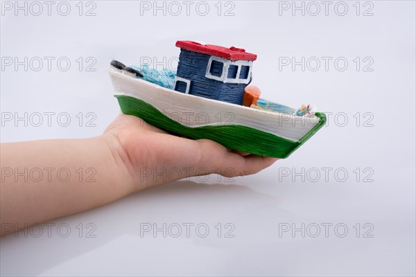 Little colorful model boat in hand on white background